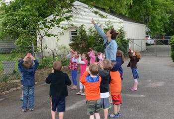 Adult and children looking up and pointing outdoors