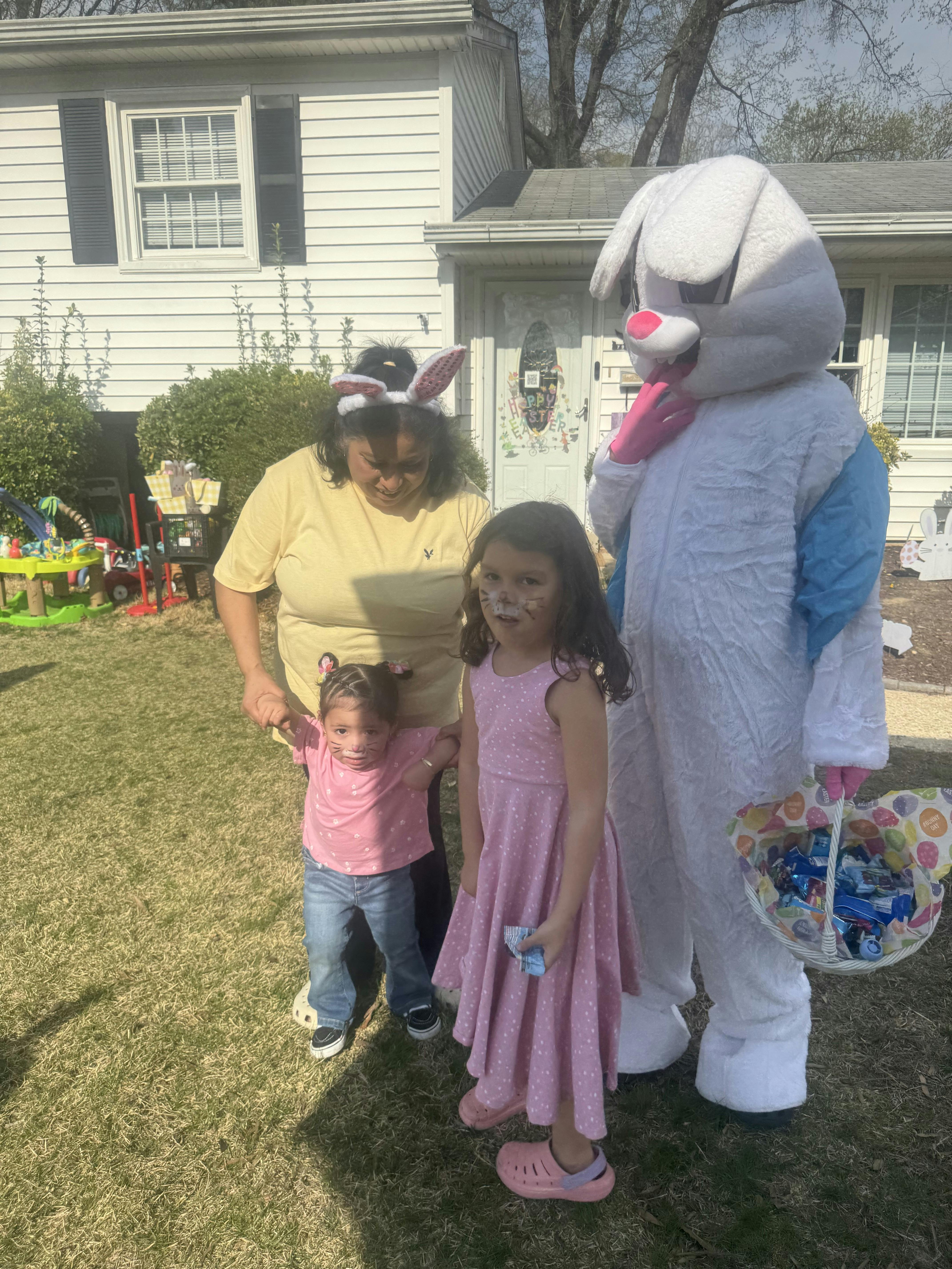 Person with two children in front of a person in an Easter bunny costume