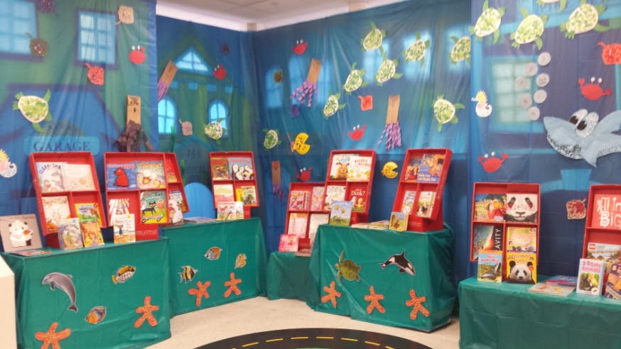 Children's books displayed on tables with an underwater-themed backdrop