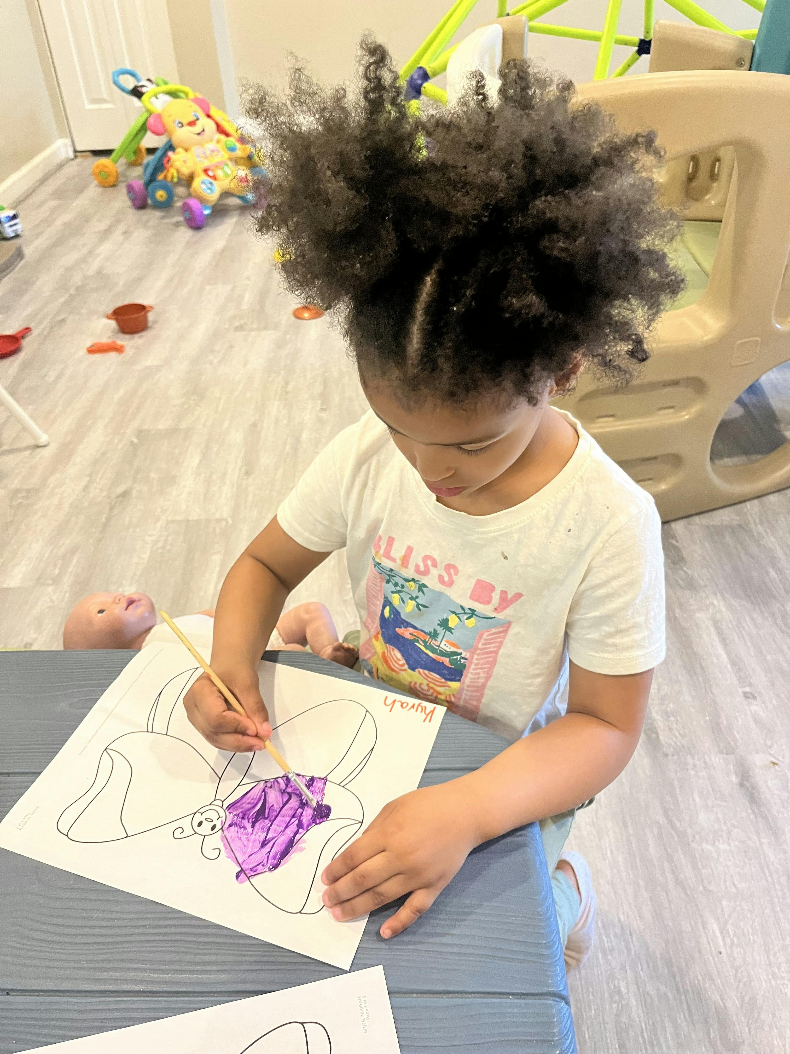 Child painting a butterfly coloring page at a table