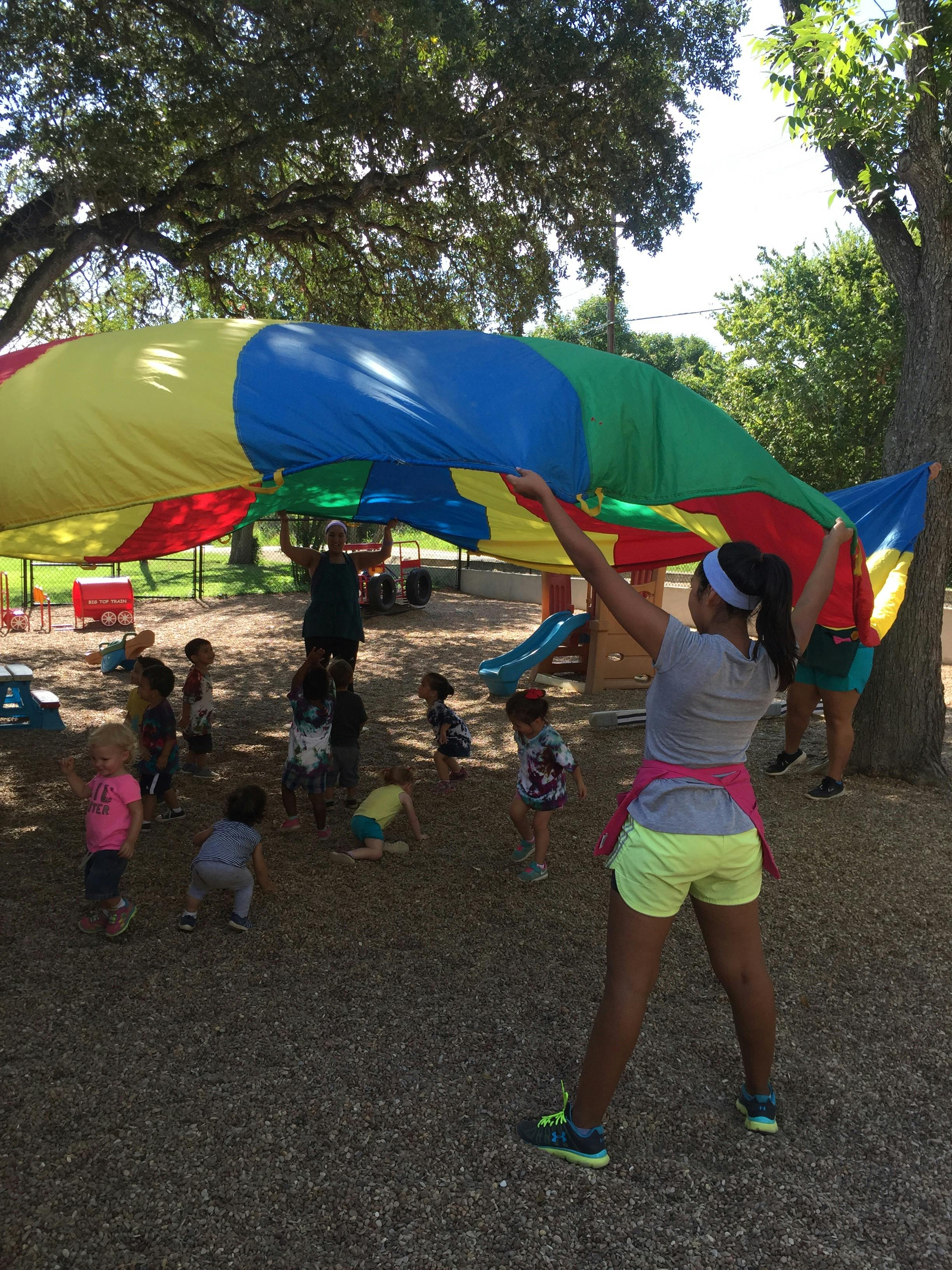 People and children playing with a colorful parachute outdoors