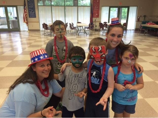 Two people and four children with face paint and patriotic hats