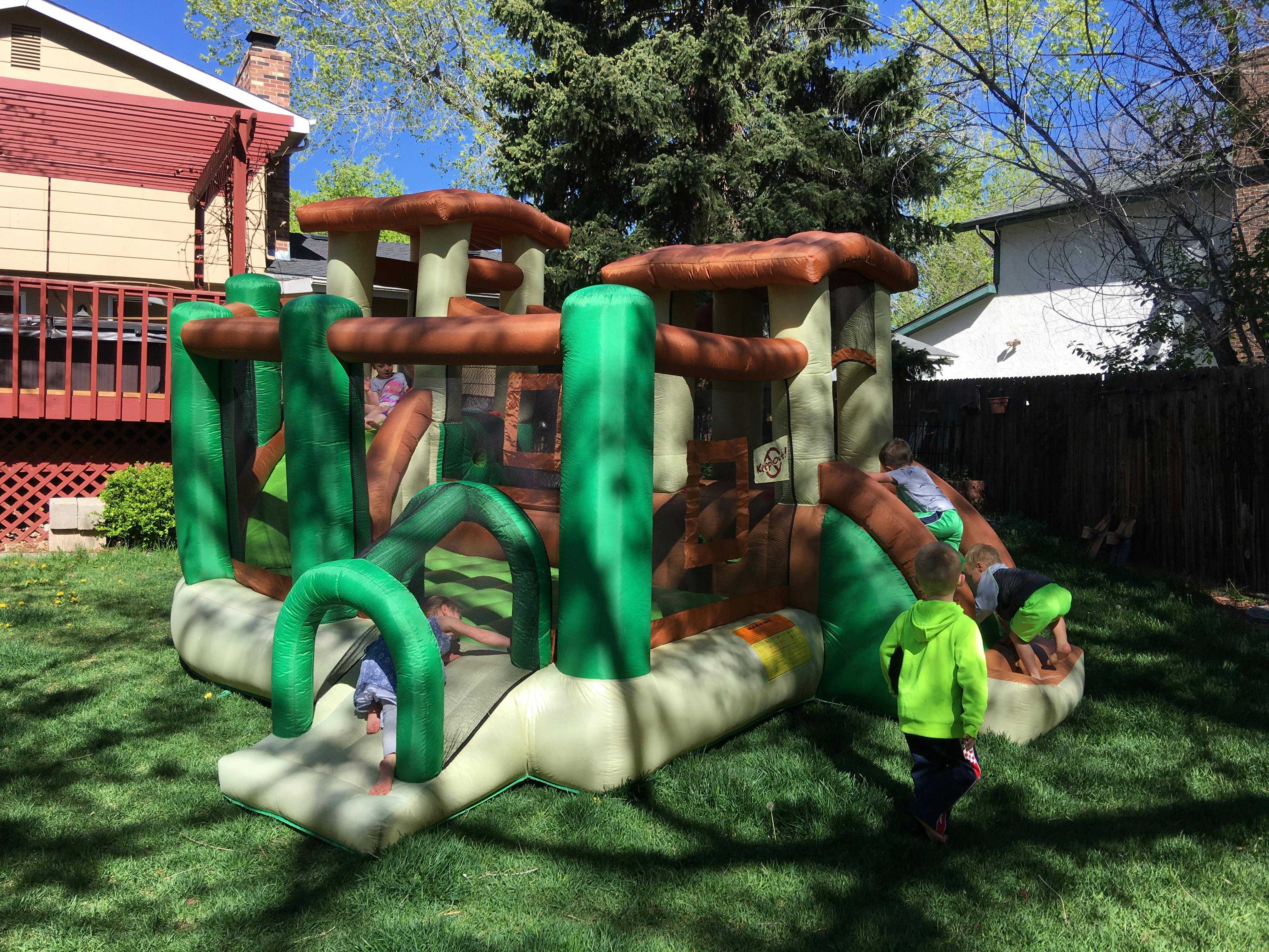 Children playing on an inflatable bounce house in a yard