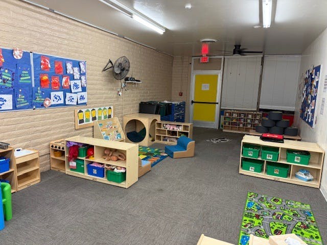 Classroom with various toys and learning materials on shelves and rugs