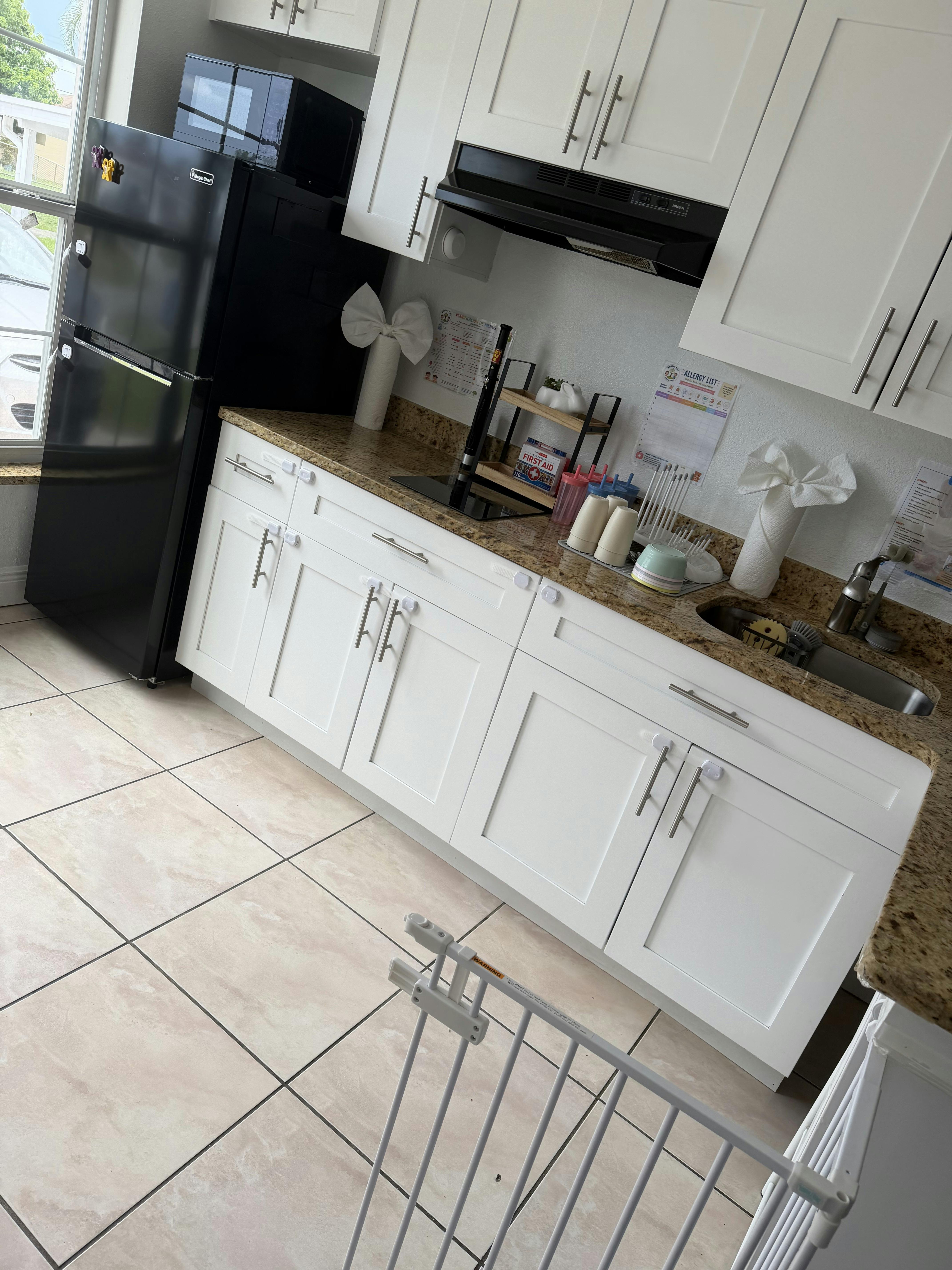 Kitchen counter with white cabinets and a black refrigerator