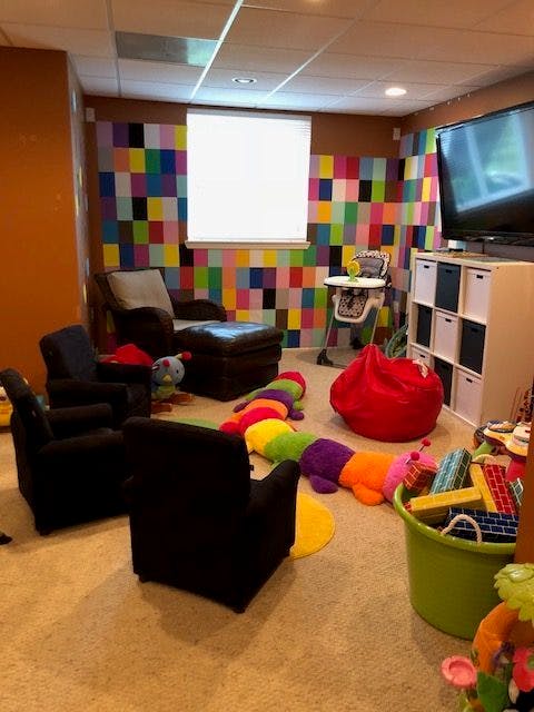 Playroom with colorful wall, chairs, toys, and television