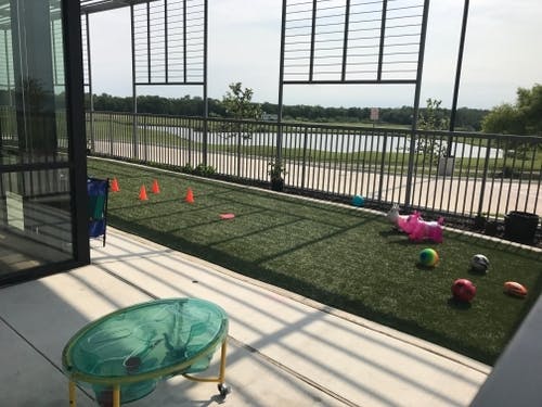 Outdoor patio with artificial turf, orange cones, and toys