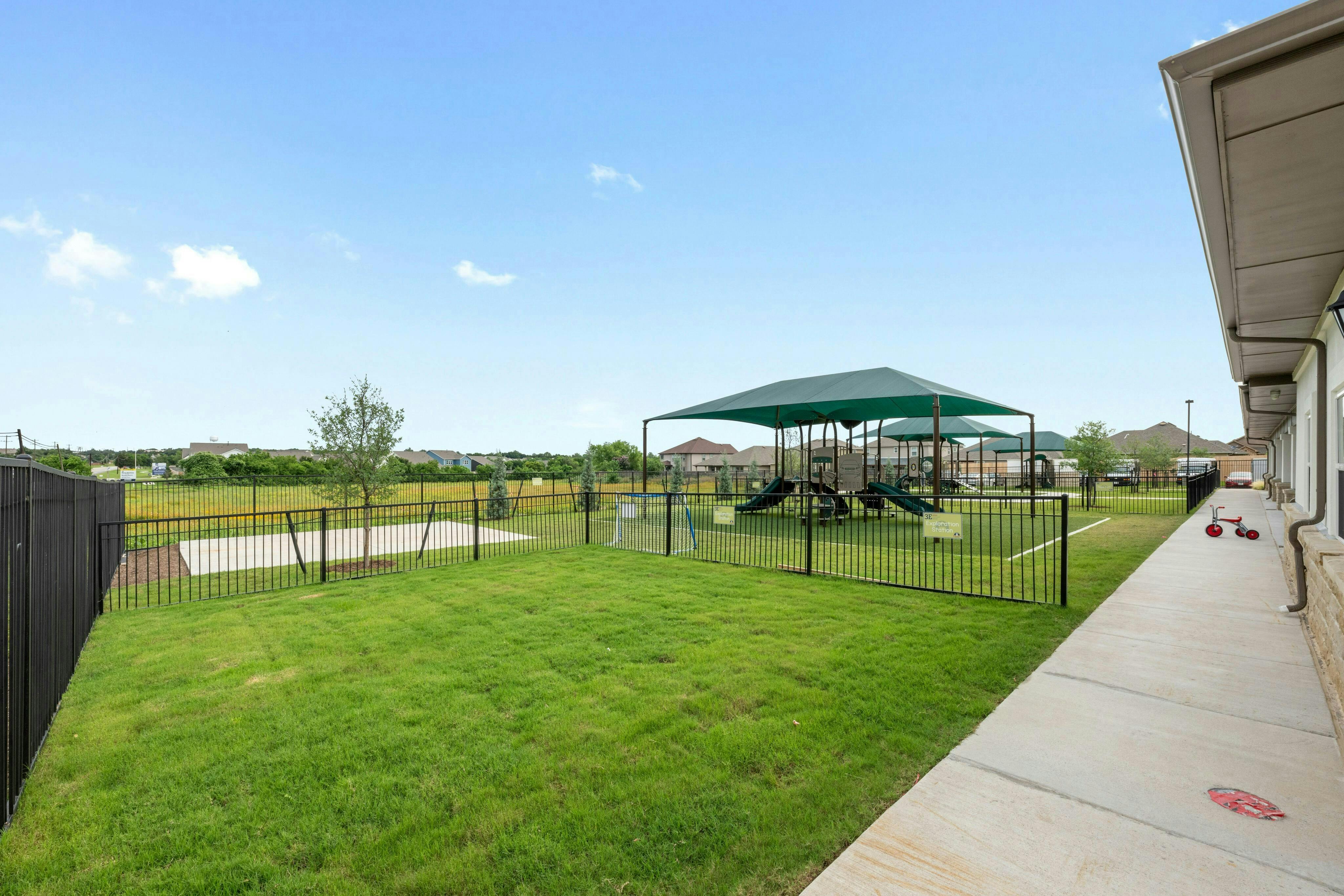 Outdoor playground with green grass and a covered play structure