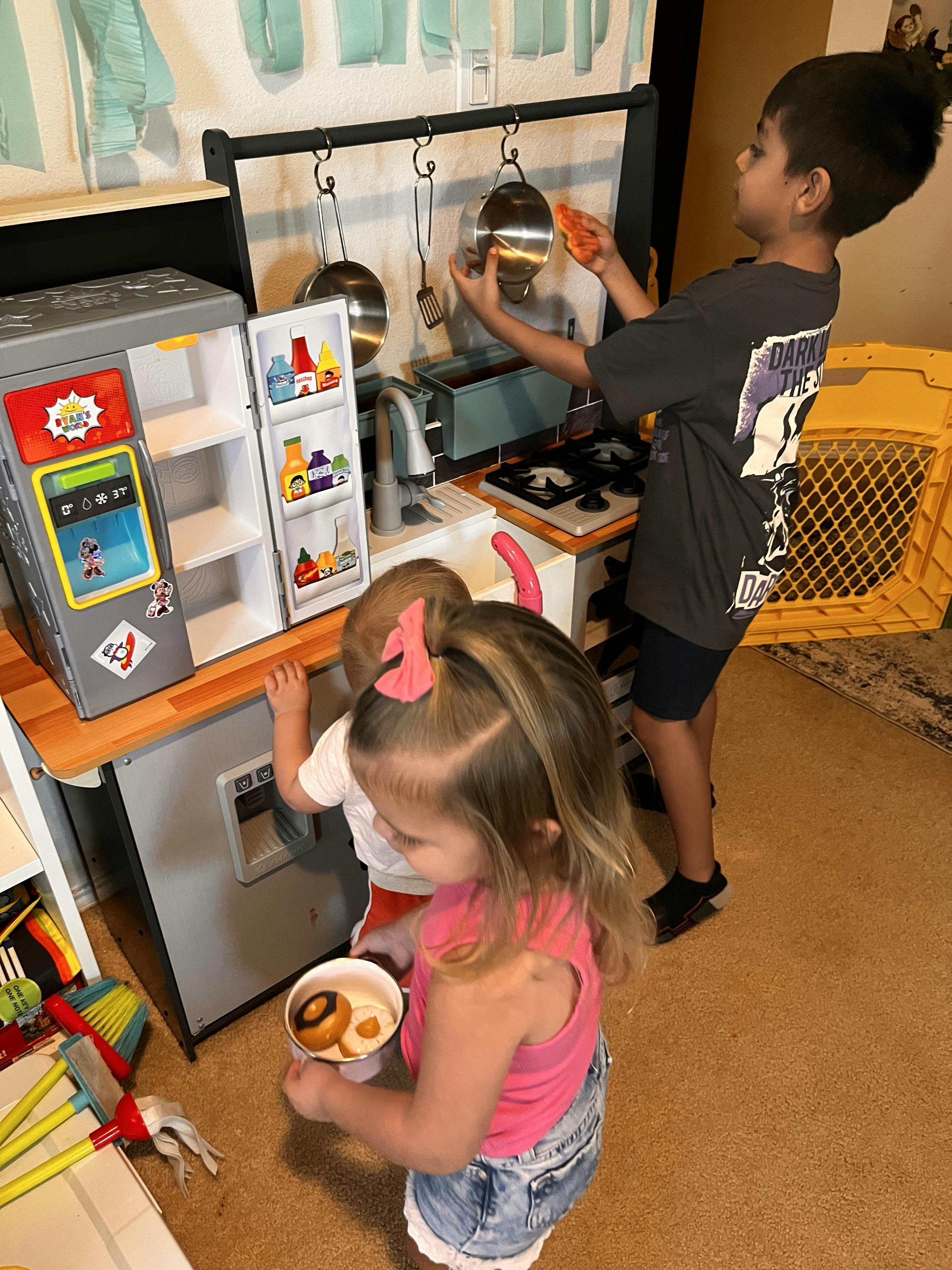 Children playing with a toy kitchen set