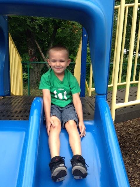 Child sitting on a blue playground slide