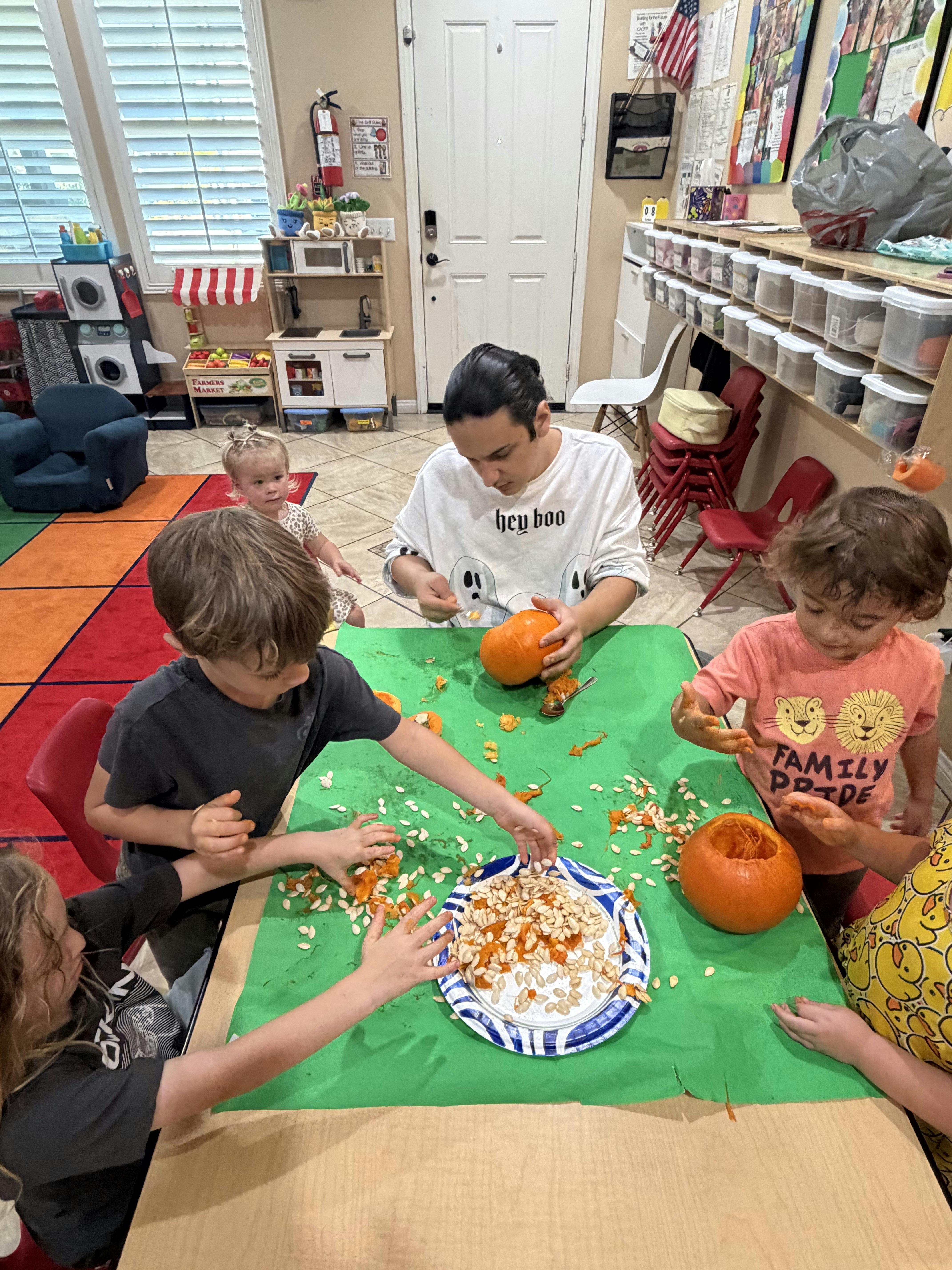 A person and children carving pumpkins at a table