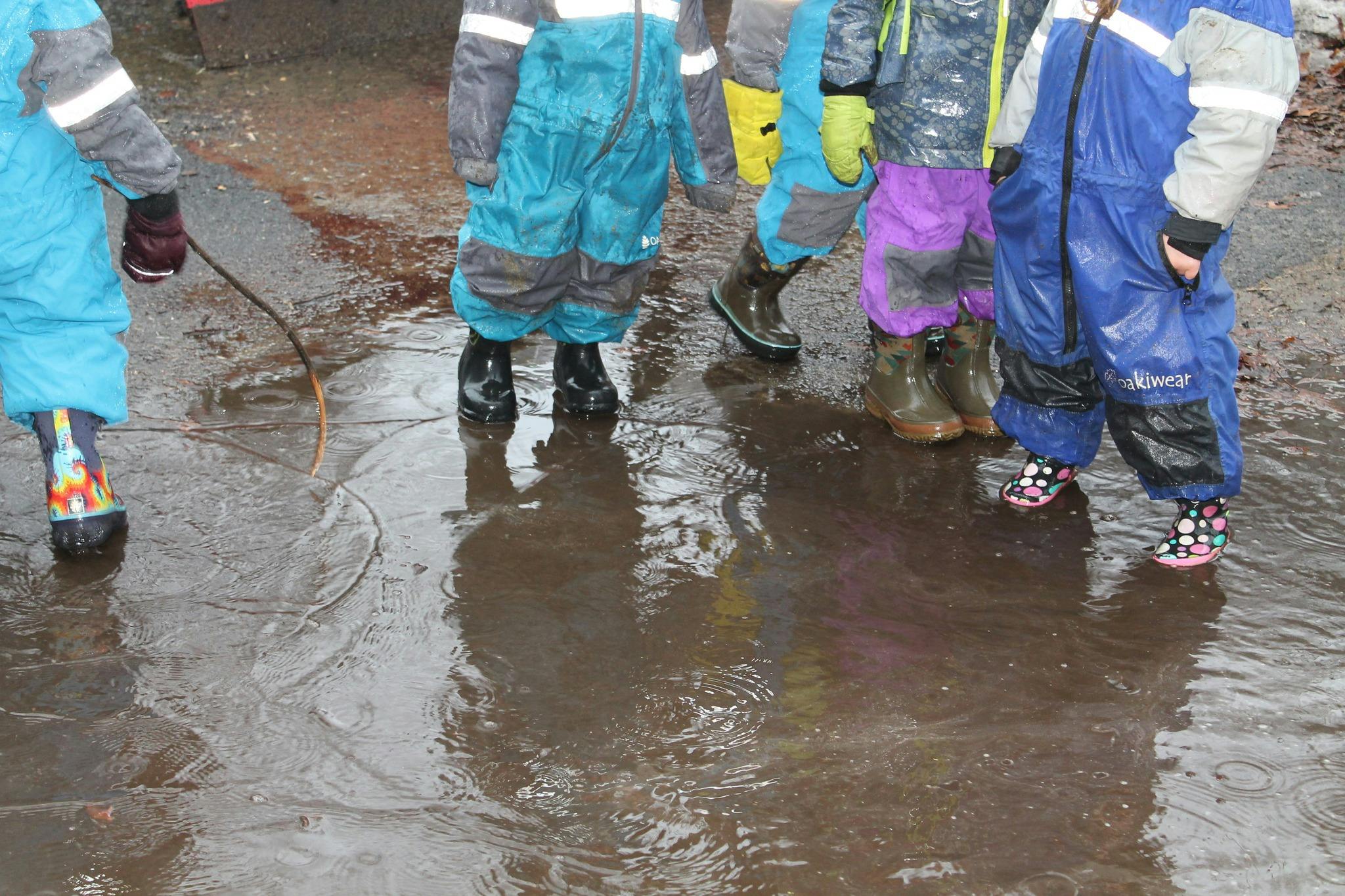 Children in rain gear standing in a puddle