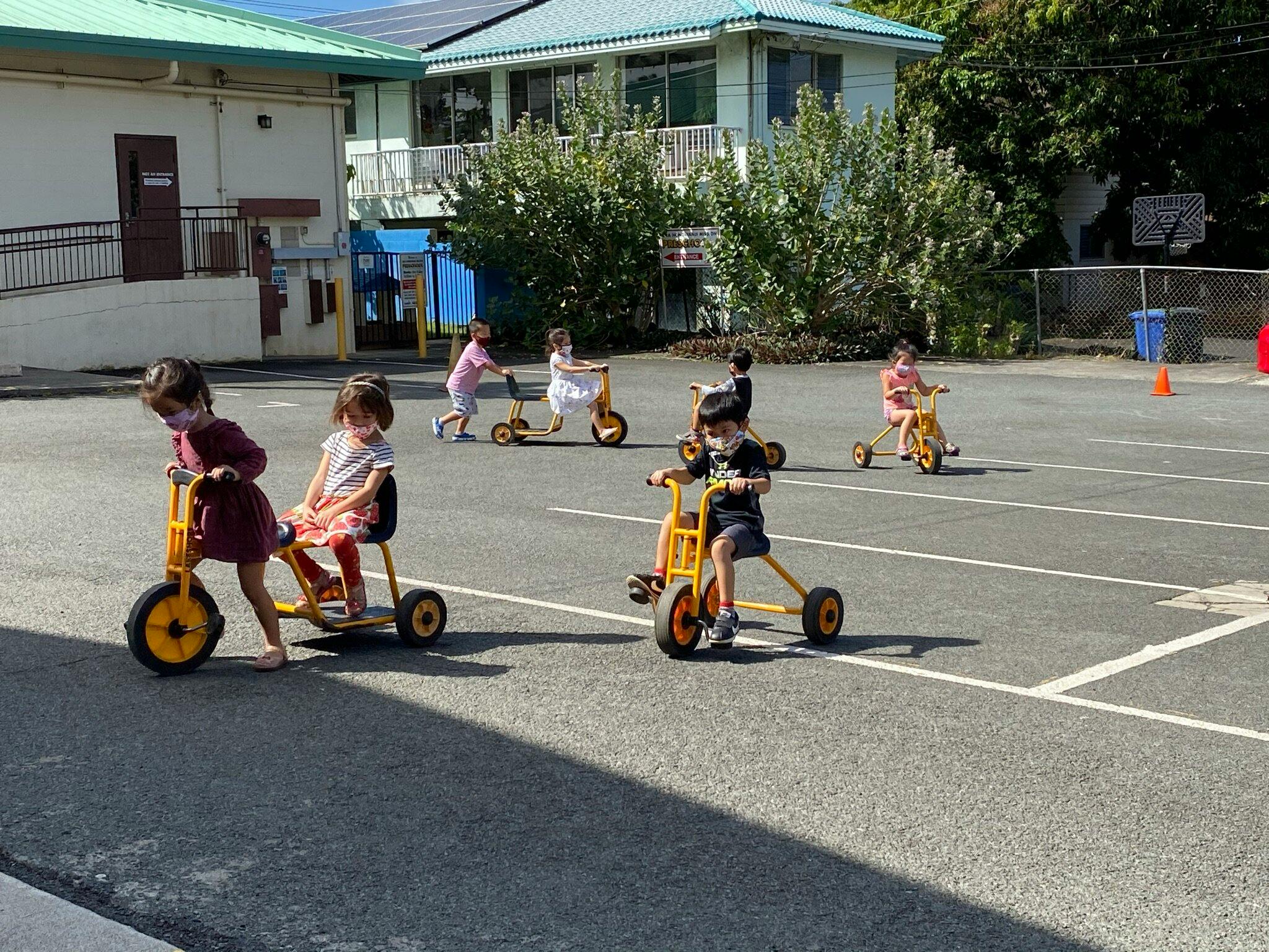 Children riding tricycles in a paved area