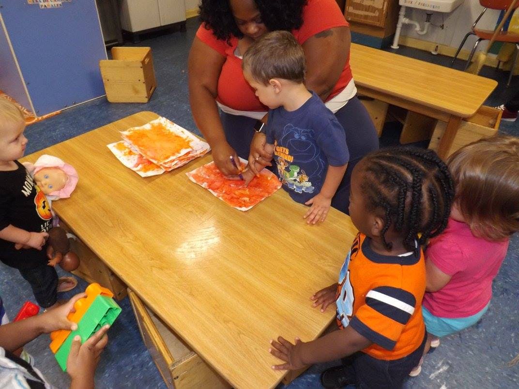 Adult and children doing an art activity at a table