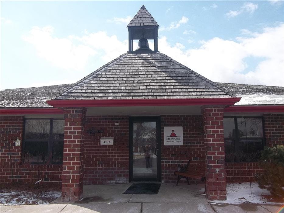 Brick building entrance with bell tower, sign reading "KinderCare Learning Center"