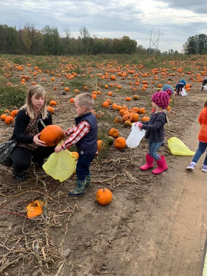 Adult and children picking pumpkins in a pumpkin patch