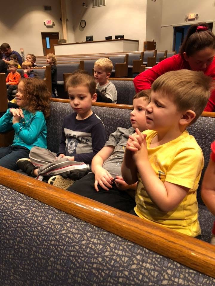 Children sitting in pews, some with hands clasped