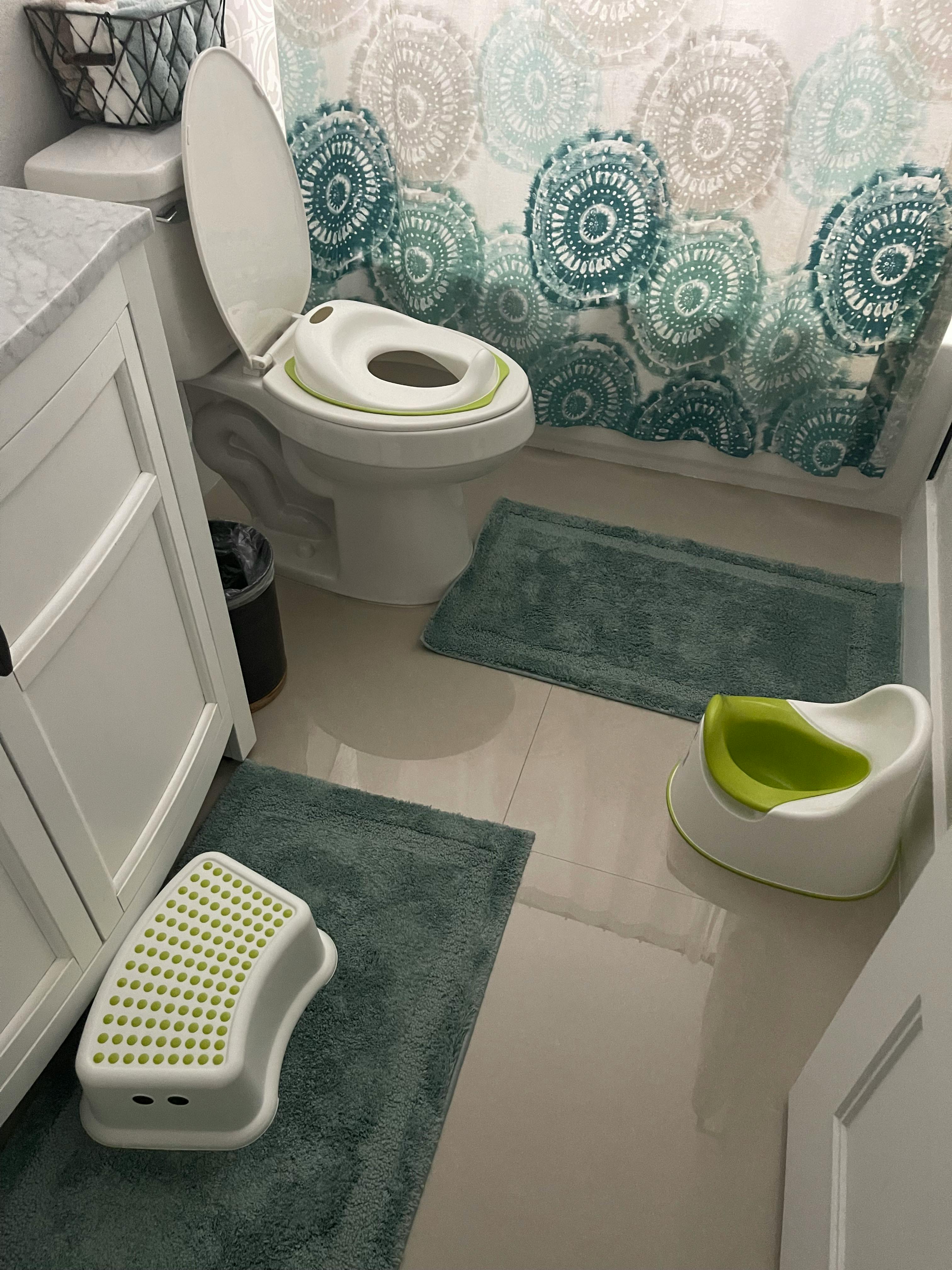 Toilet with a child seat, a potty, and a step stool in a bathroom