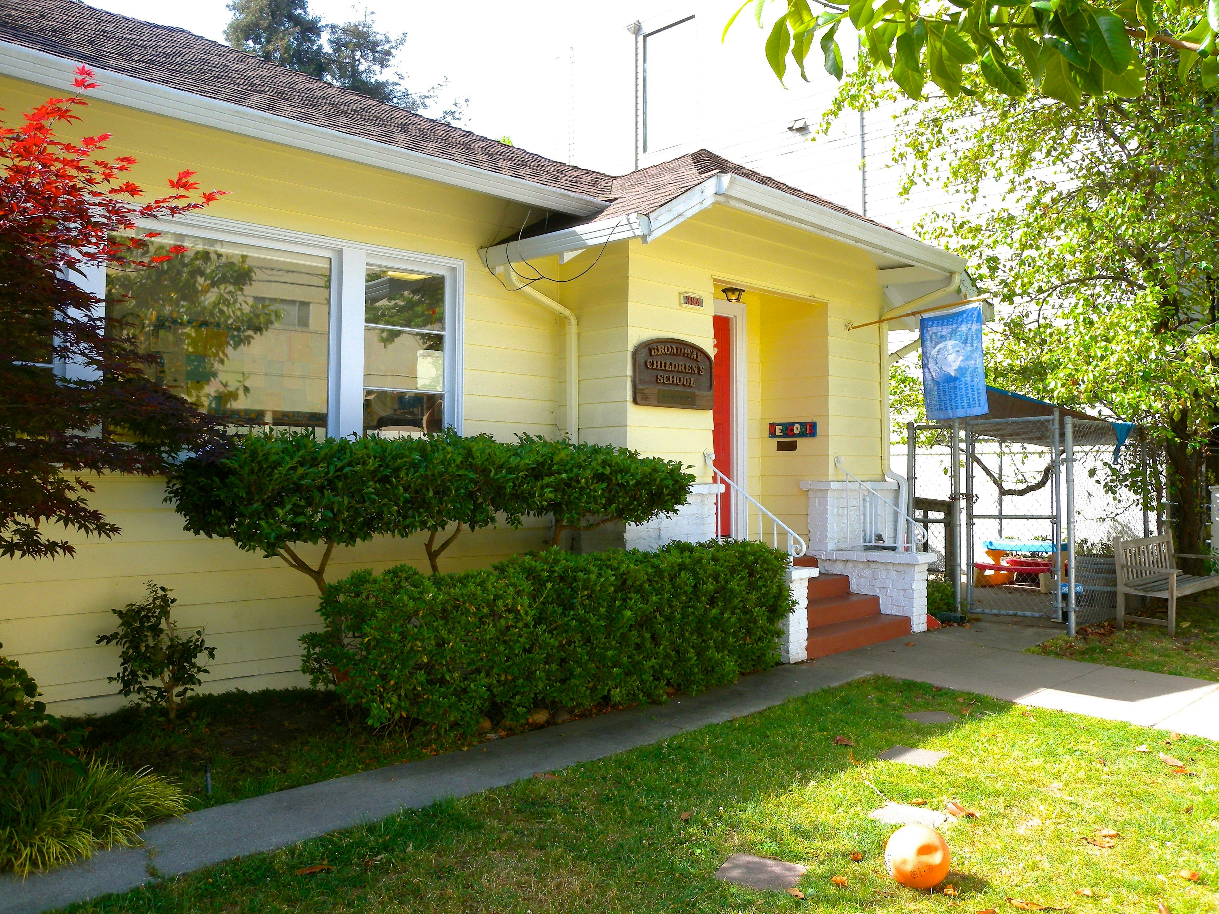 Yellow house with red door and white porch railing