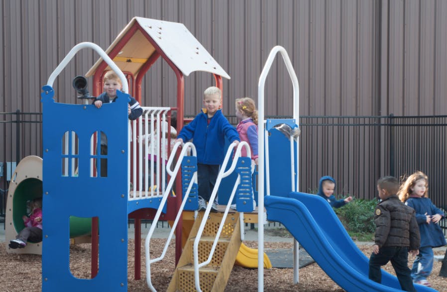 Children playing on a blue and red playground structure