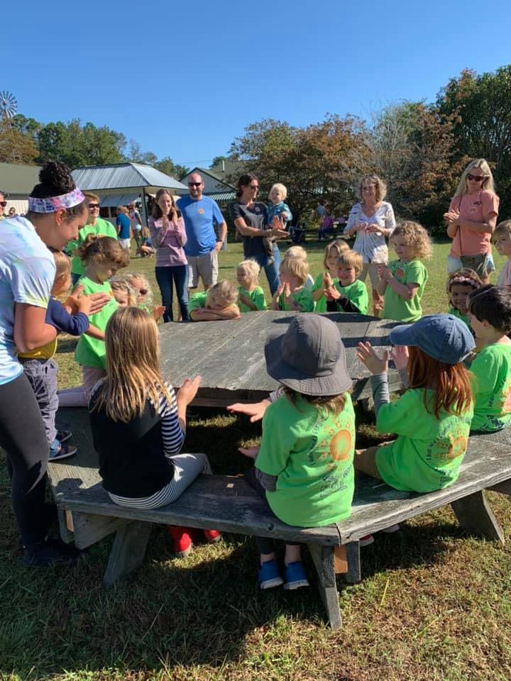 Adults and children gathered around a picnic table outdoors
