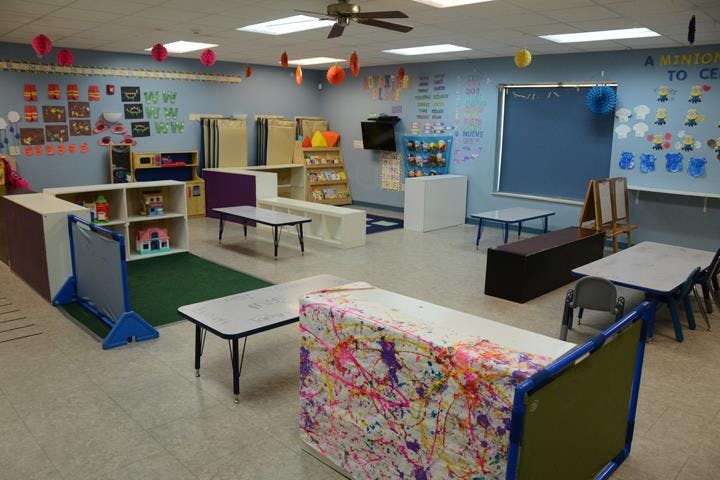 Classroom with small tables, chairs, and shelves