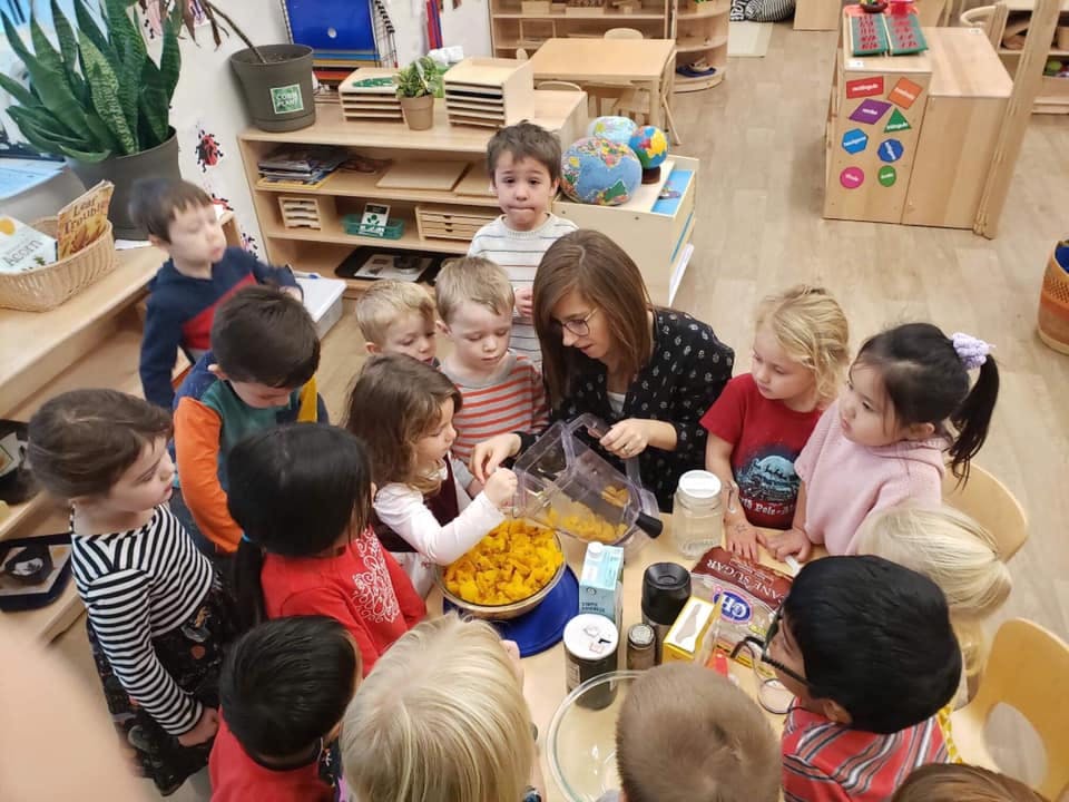 Adult and children gathered around a table with a bowl of food