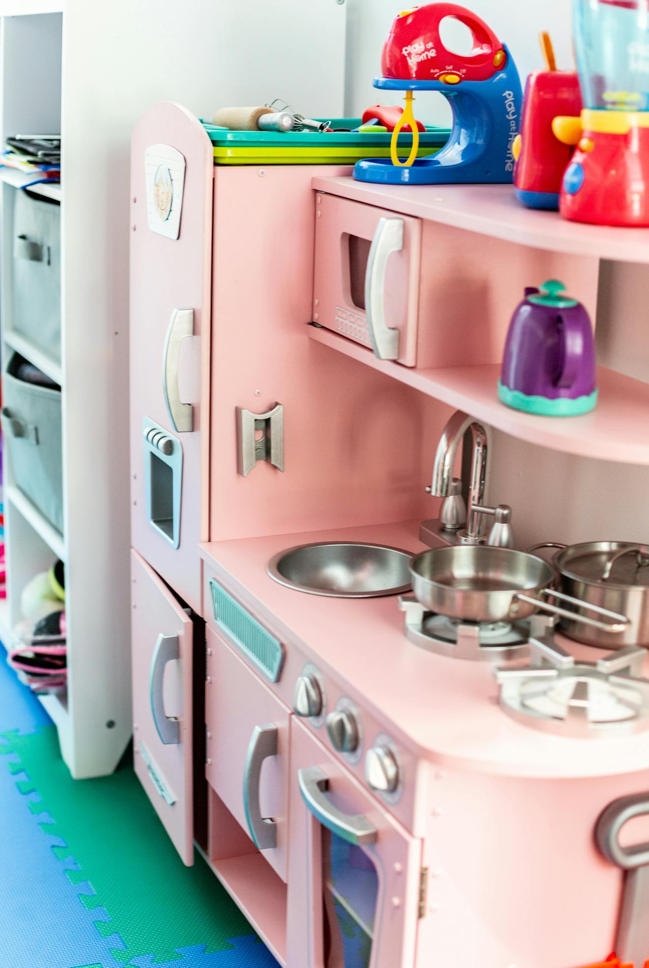 Pink toy kitchen with sink, stove, and play food mixer