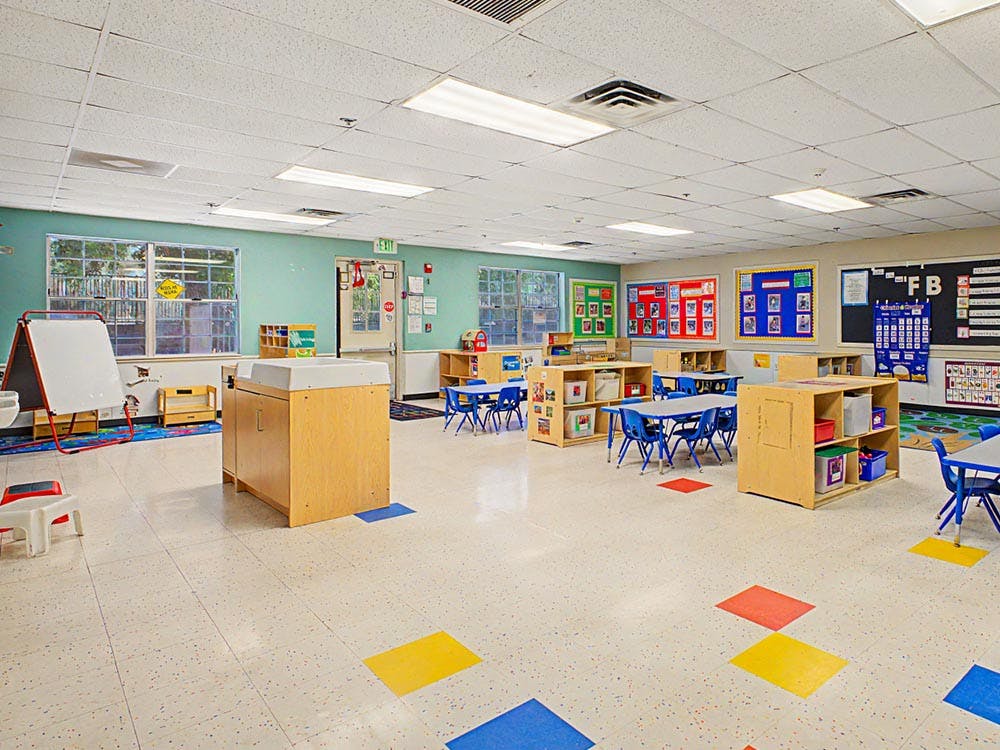 Empty classroom with small tables and chairs, and learning materials