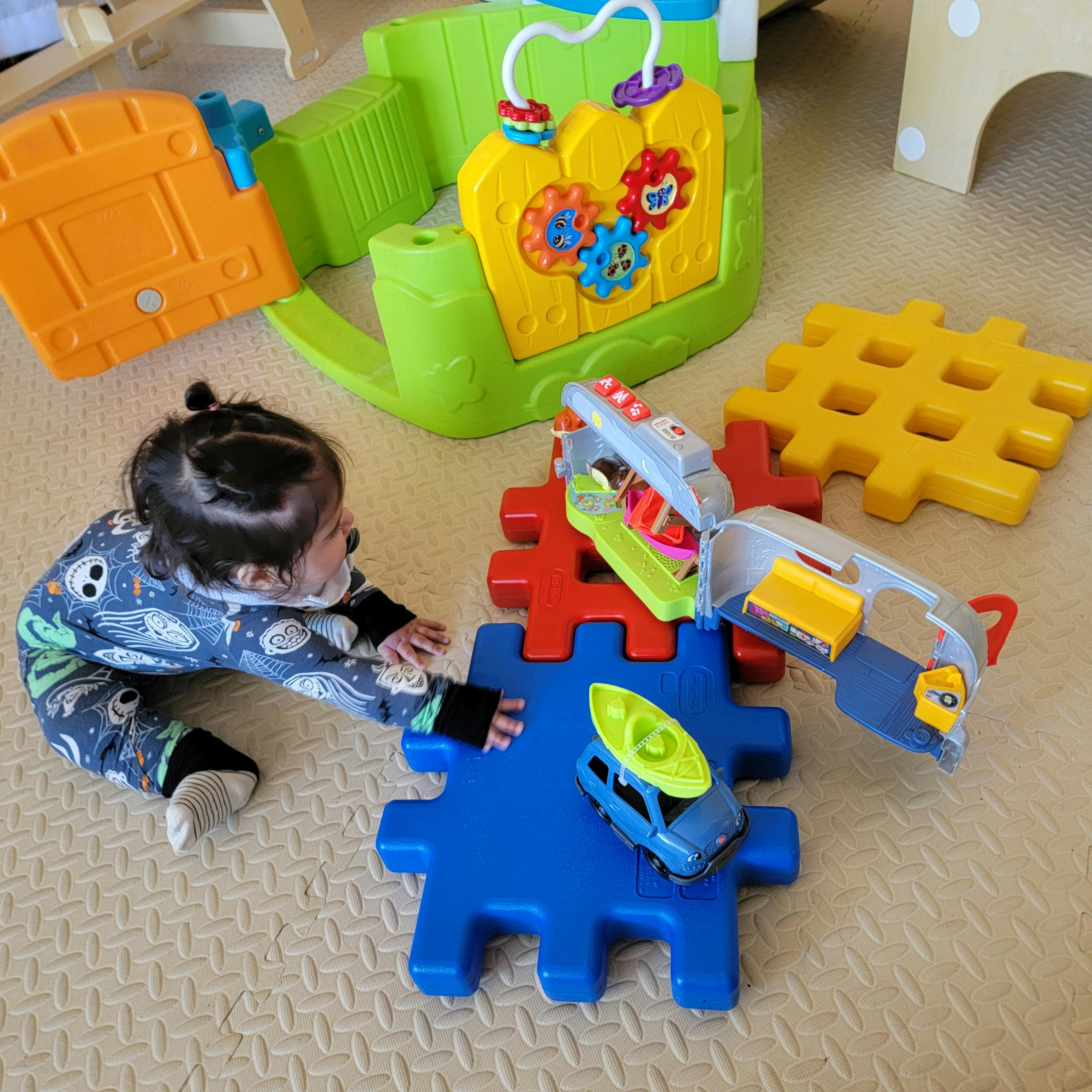Child on floor reaching for toys