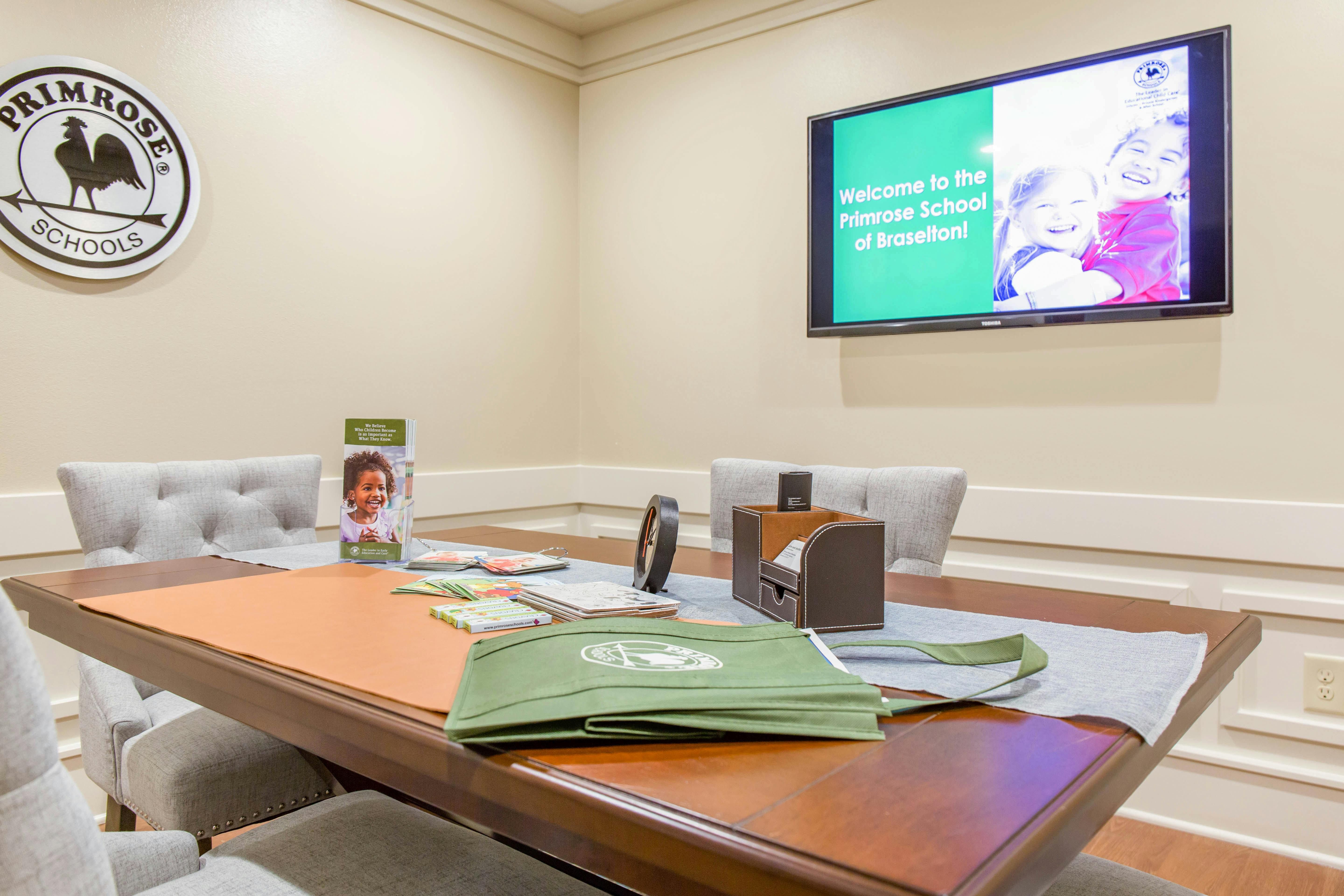 Meeting room with a table, chairs, Primrose Schools sign, and TV screen