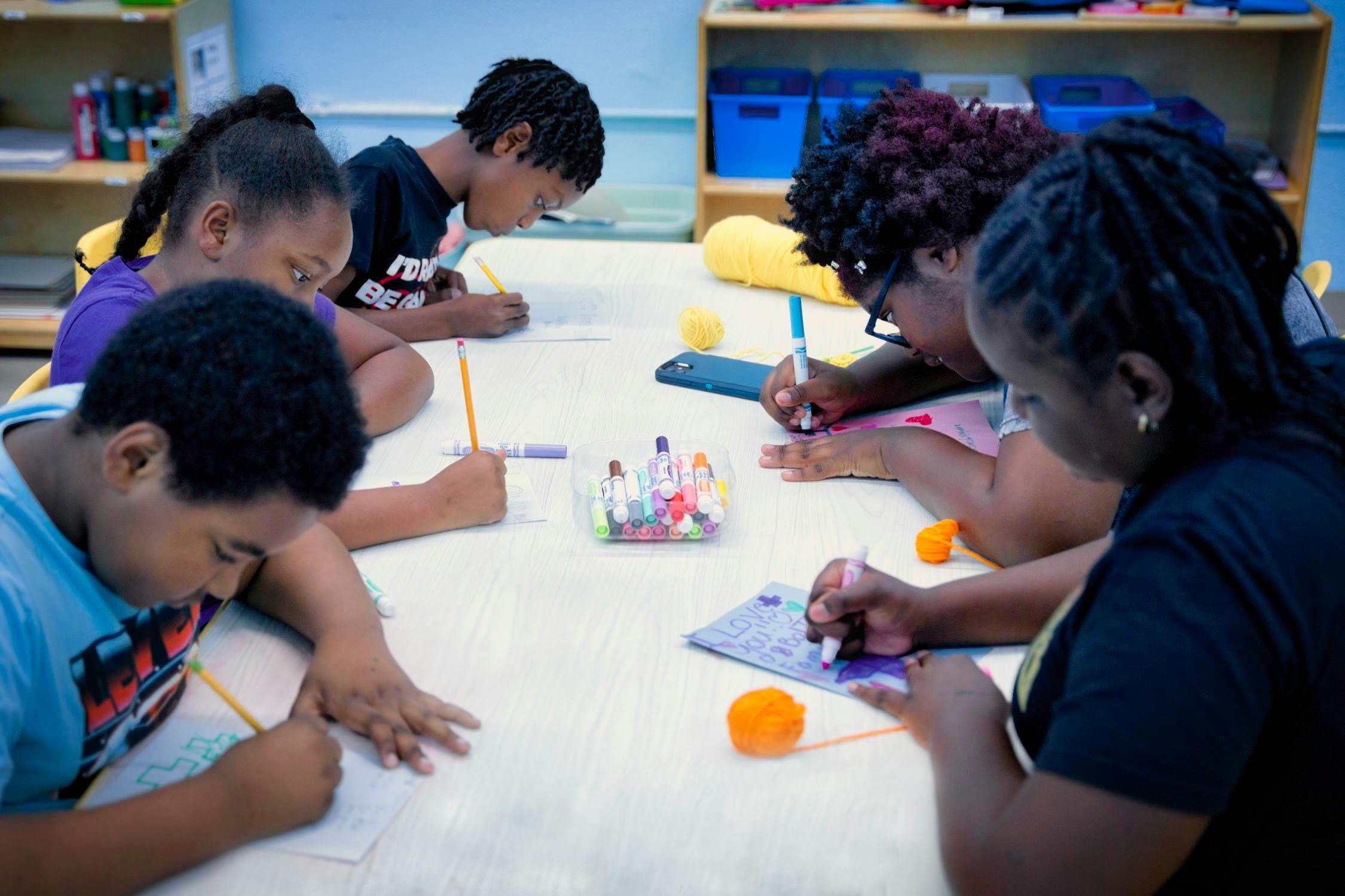 Children and adults drawing at a table