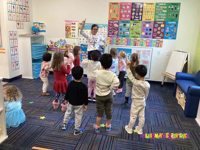 Adult teacher interacting with a group of children in a classroom