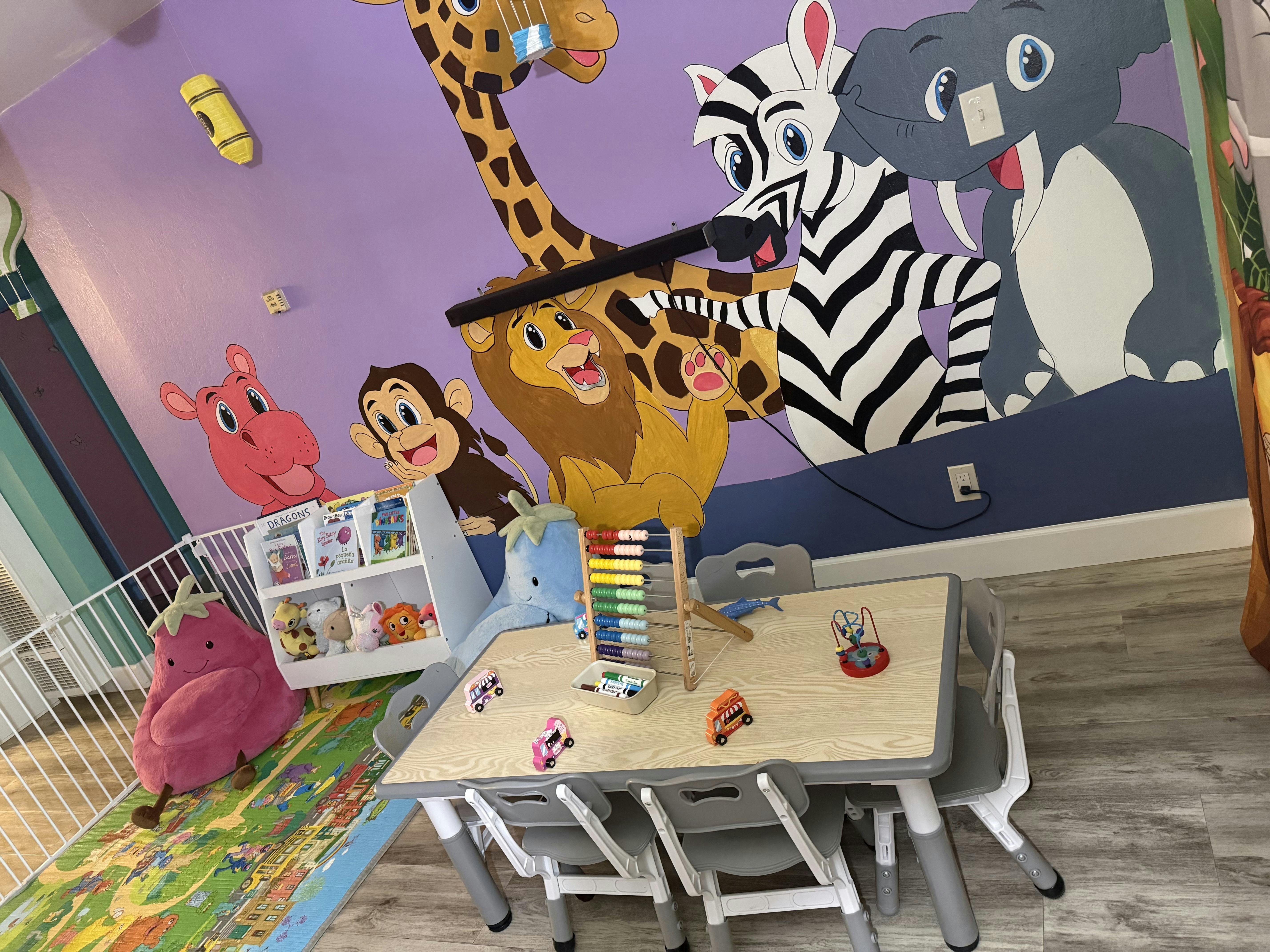Child playroom with animal mural, table, chairs, and books