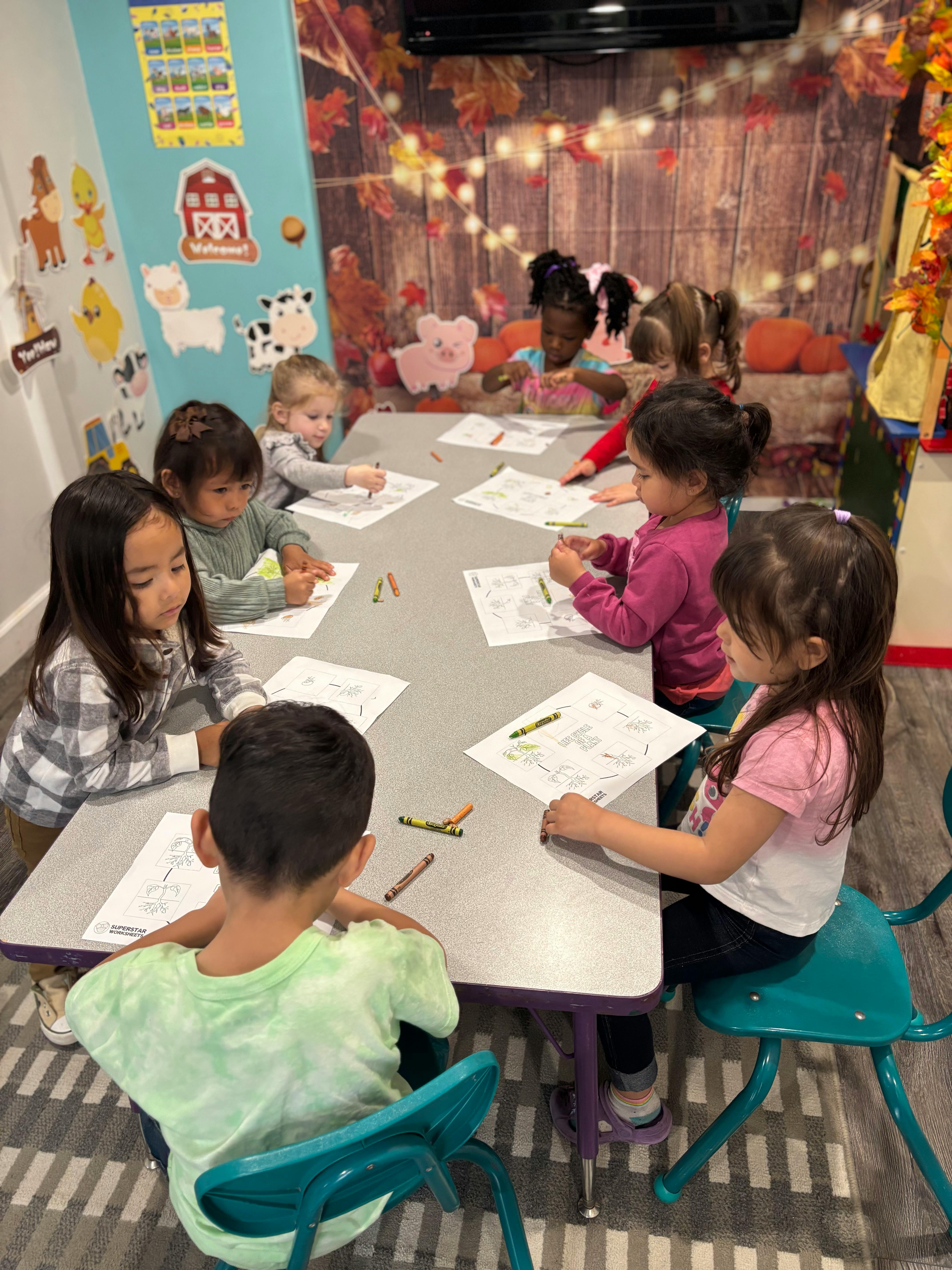 Children sitting at a table coloring on paper