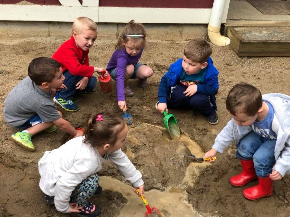 Six children playing in dirt with shovels and buckets