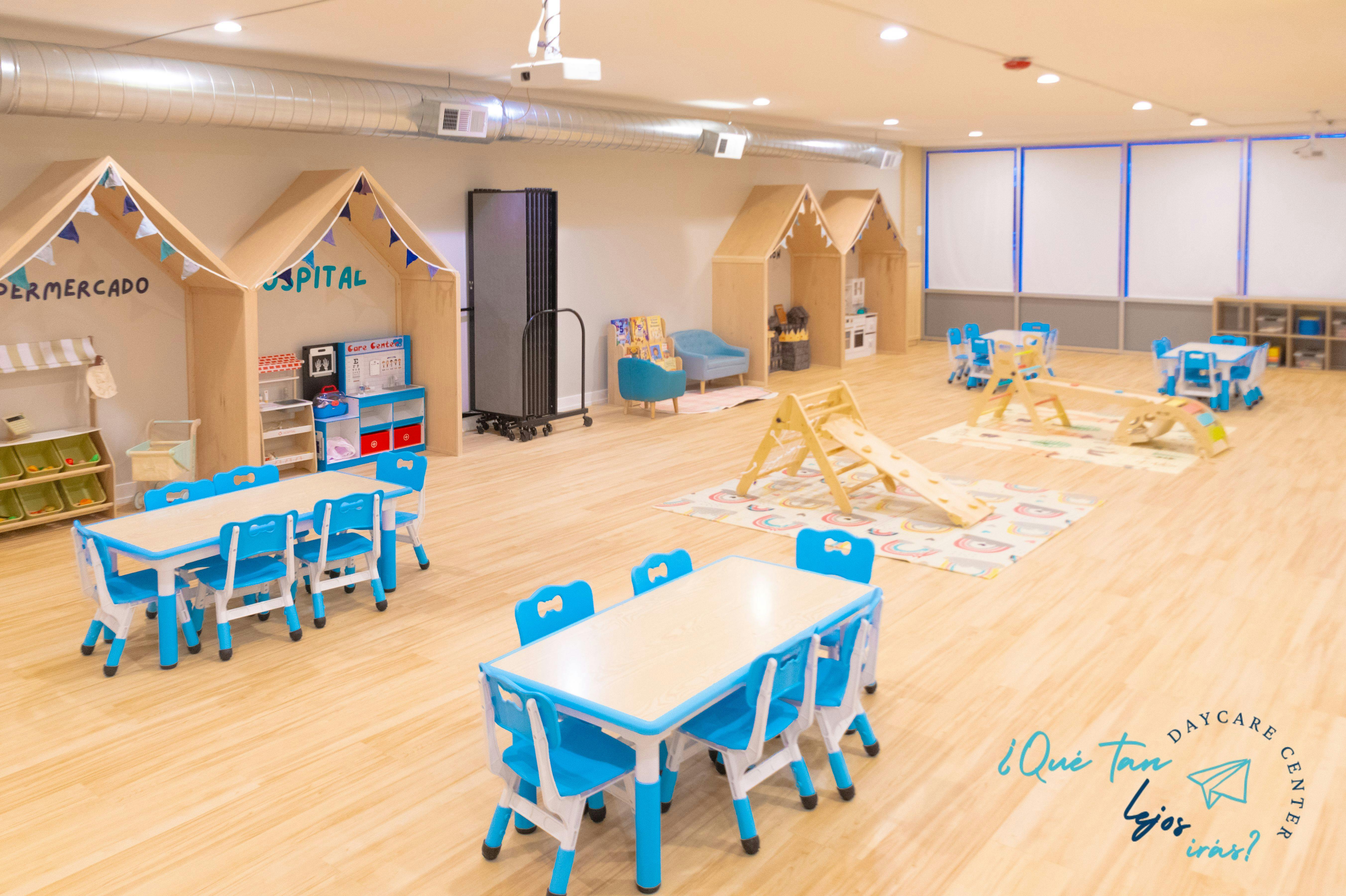 A playroom with small tables and chairs, playhouses, and an indoor slide