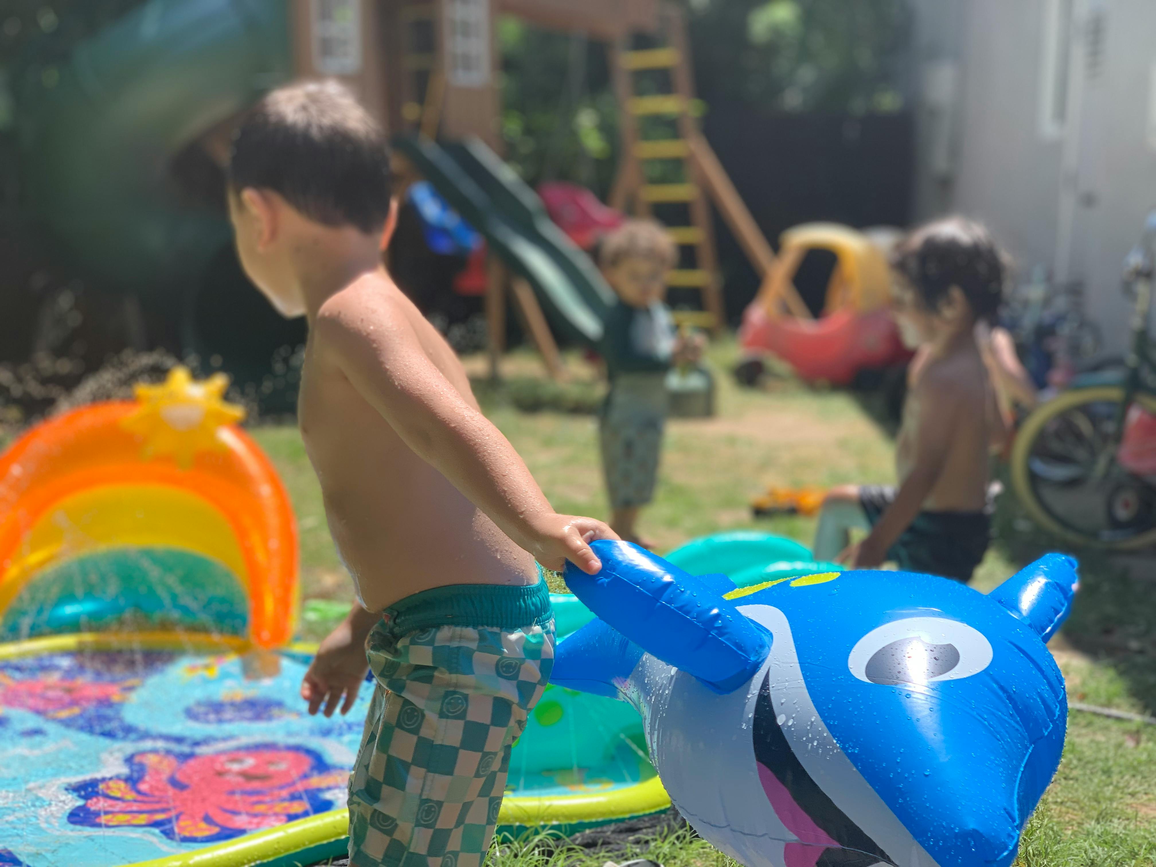 Child playing with an inflatable dolphin toy in a yard