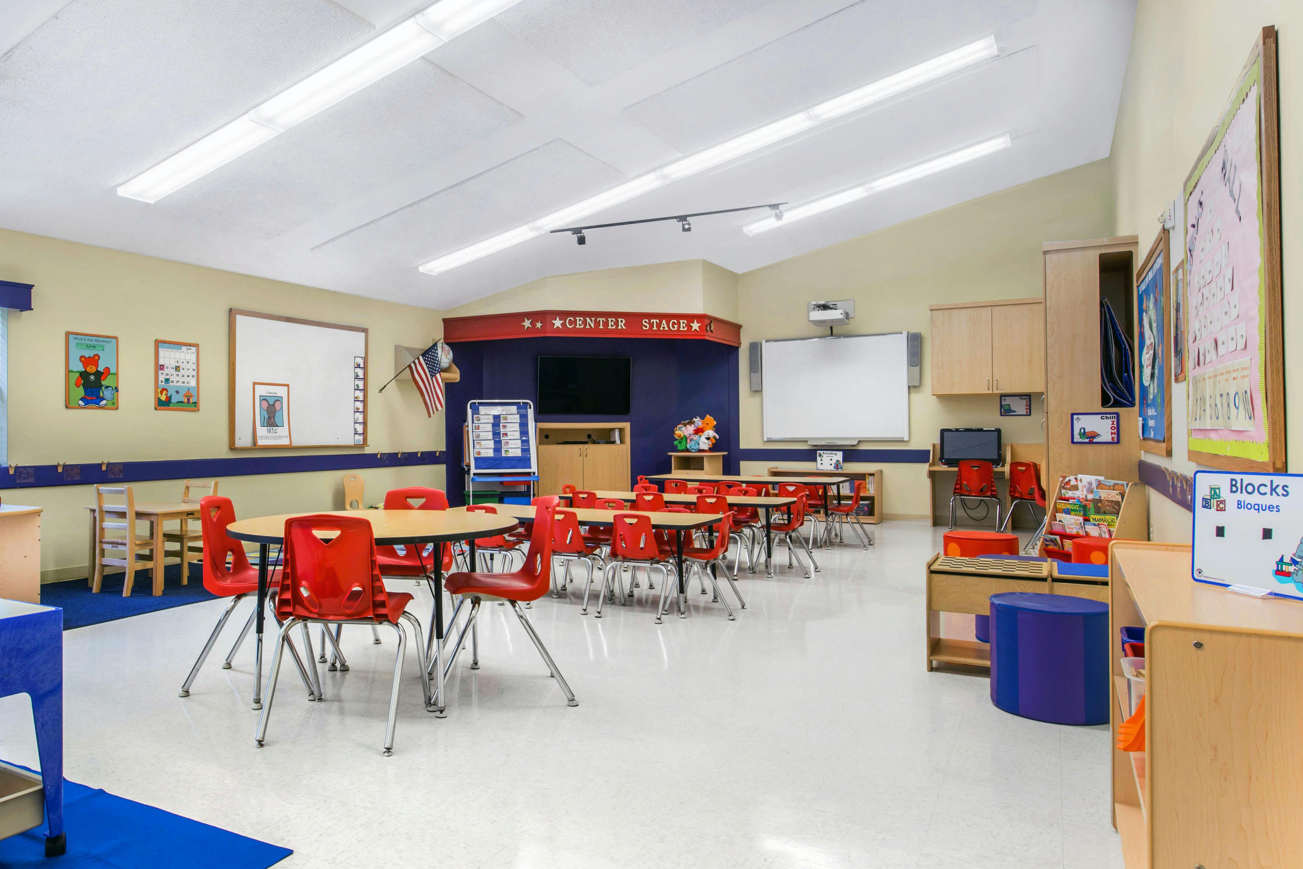 Classroom with small tables and chairs, whiteboards, and a "CENTER STAGE" sign