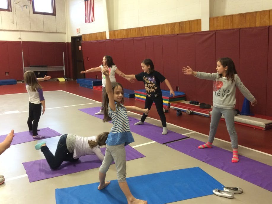Children doing yoga poses on mats in a gym