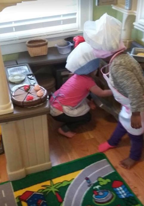 Two children playing in a toy kitchen
