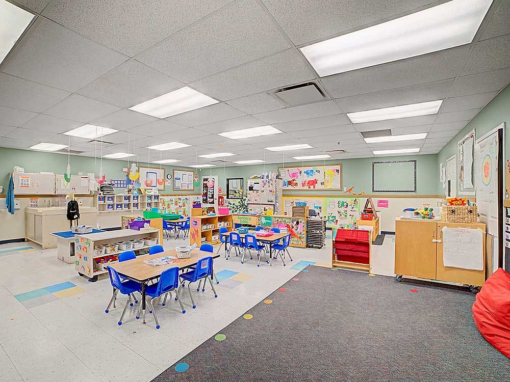 Empty classroom with small blue chairs around tables