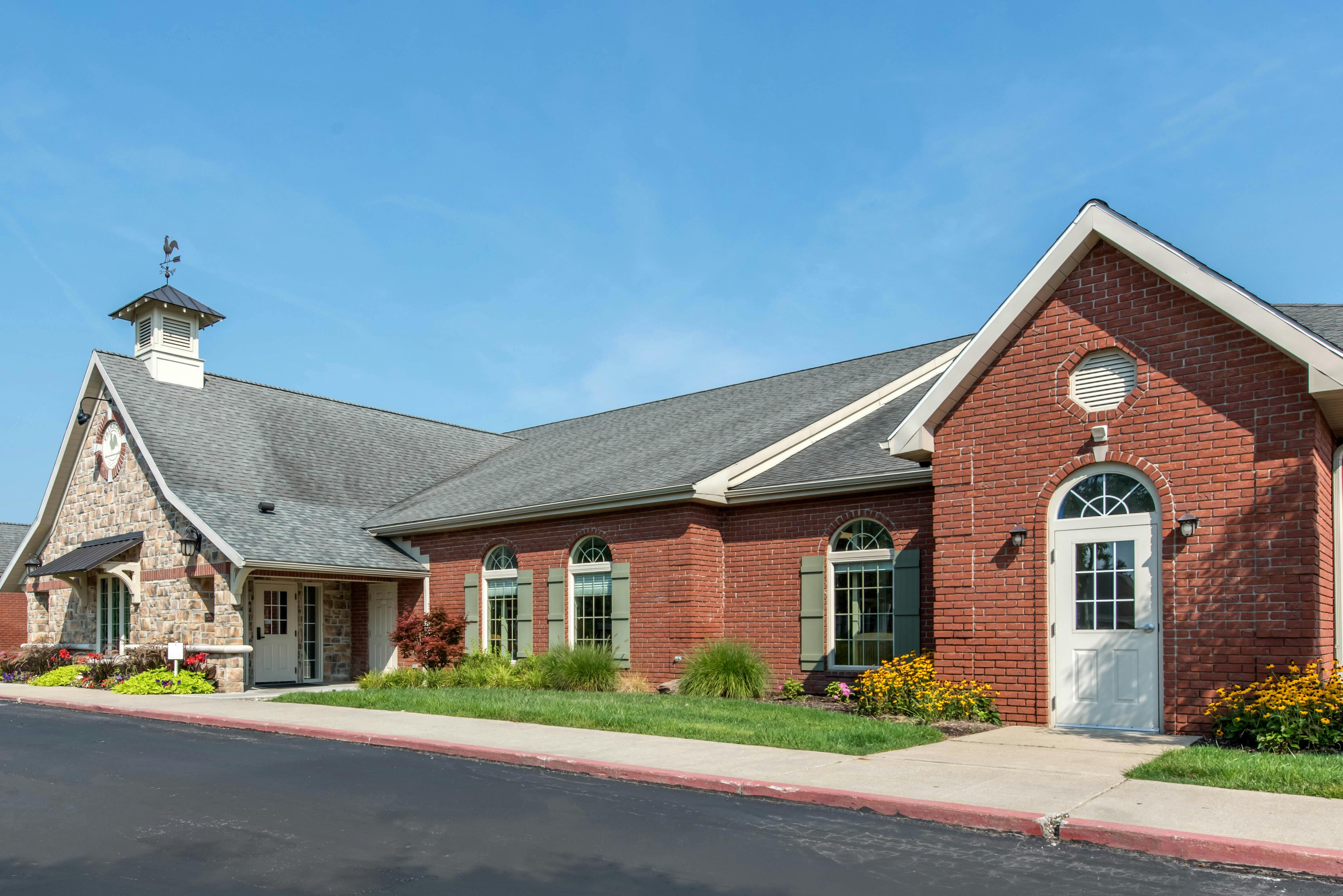 Building with brick and stone facade, cupola with weather vane, and arched doorways