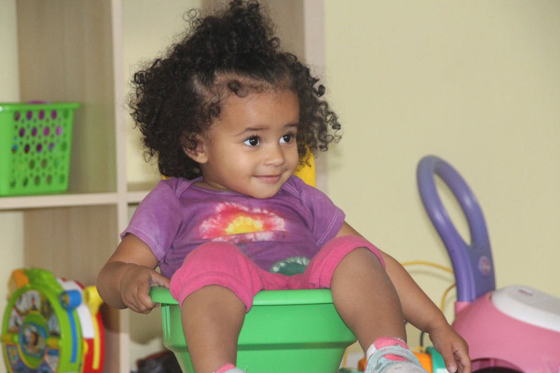 Child sitting in a green toy