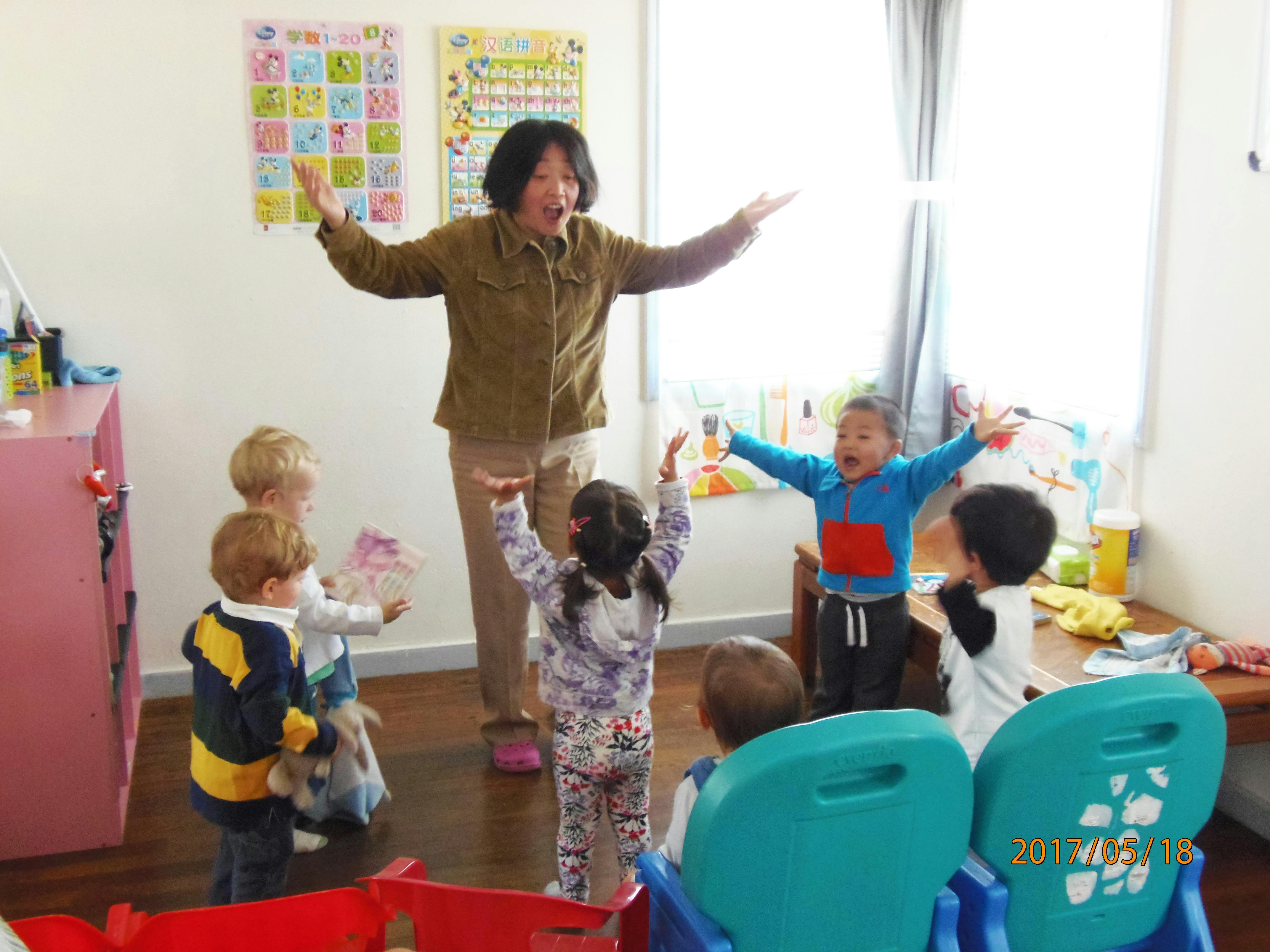 Person with arms out leading children in an activity