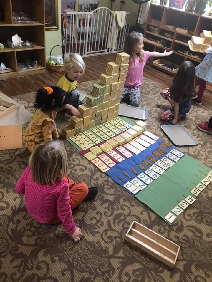 Children playing with educational blocks and number mats on the floor
