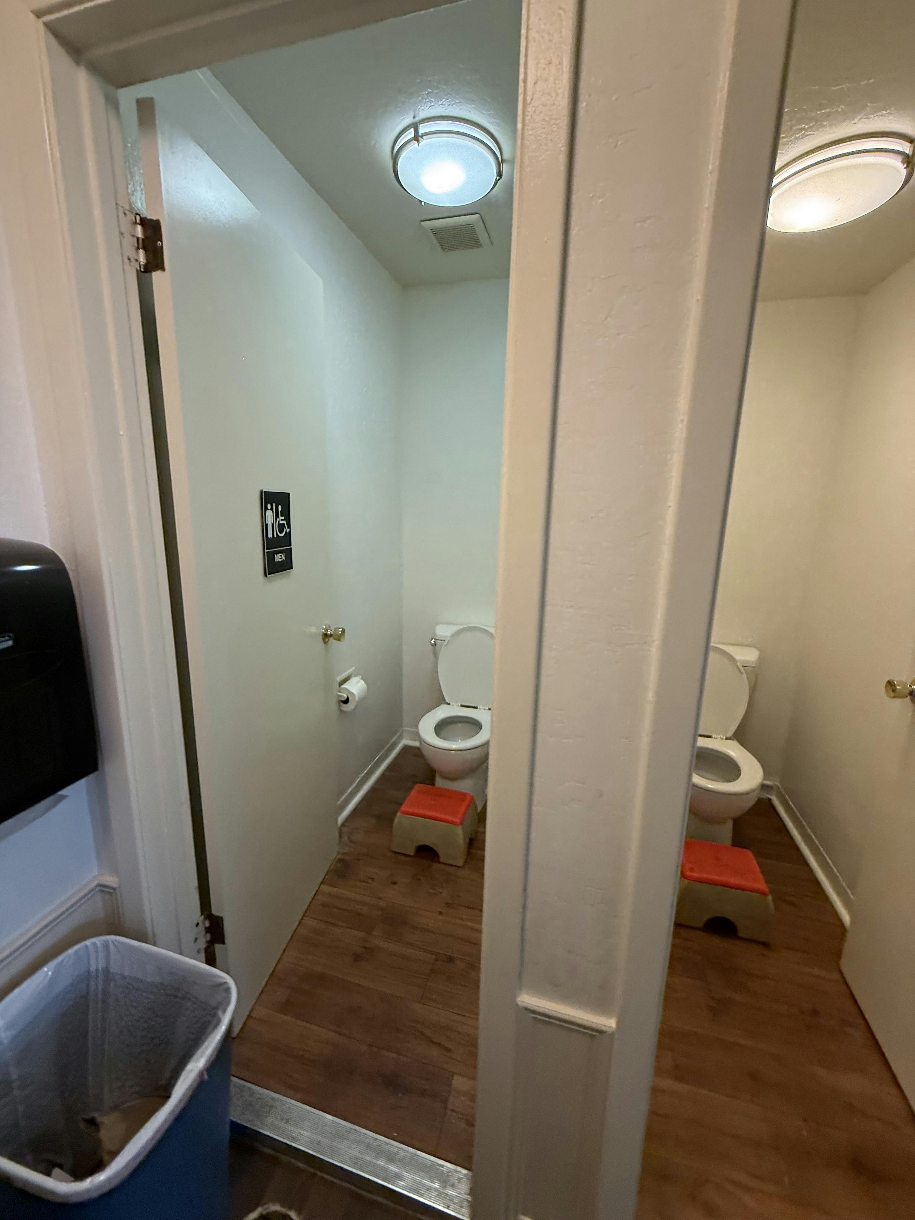 A public restroom with two toilets, each with a red step stool