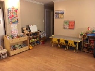 Children's play area with small tables and shelves of toys