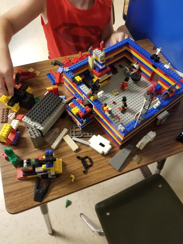 Child's hands building with colorful toy bricks on a wooden table