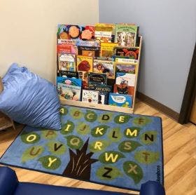 Bookshelf with books, blue alphabet rug, and blue beanbag chair